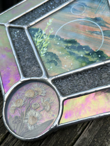 Floral close up. Gouache landscape set between glass with pressed wildflowers. Iridescent pink and textured clear glass border.